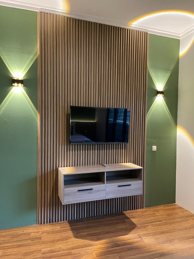 Ruang TV Sampai Living Townhouse dengan panel kayu dan aksen hijau